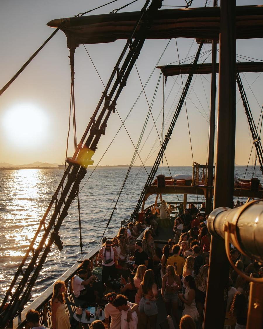 Guests on the deck of the Barco De Pirata sunset party cruise at golden hour off Kos.